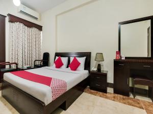 阿吉曼Al Rayan Hotel的一间卧室配有一张带红色枕头的床和一张书桌