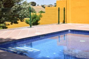 MéntridaCASA CAPELLANIA-chalet con piscina junto a Madrid的黄色围栏前的游泳池