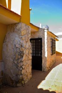 MéntridaCASA CAPELLANIA-chalet con piscina junto a Madrid的石头建筑,有门和石墙