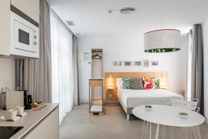 科尼尔-德拉弗龙特拉Apartamentos y estudios céntricos Conil Home Suite的酒店客房设有一张床铺、一张桌子和一间厨房。