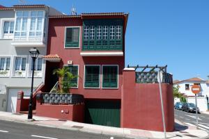 拉奥罗塔瓦La Orotava vacational rental home的街道上一座红色的建筑,设有绿色百叶窗