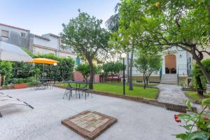 陶尔米纳Villa Valverde Apartments e B&B的庭院配有桌椅和遮阳伞。