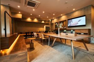 大阪&AND HOSTEL HOMMACHI EAST的一间带大桌子和电视的用餐室