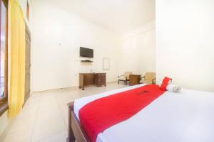 古邦RedDoorz near Nusa Cendana University的一间卧室配有一张床铺,床上铺有红色毯子