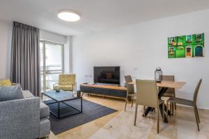 特拉维夫DIZENGOFF SQUARE superb 1 bedroom with balcony的带沙发、桌子和电视的客厅