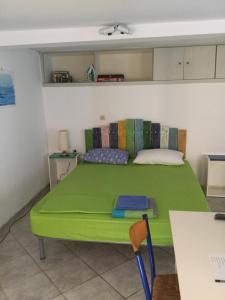 米蒂利尼studio in old town of Mytilene的一张绿色的床,位于带桌子的房间