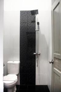 日惹纳尔姆曼特里加温酒店的一间带卫生间和玻璃淋浴间的浴室