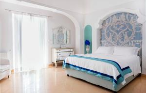 波西塔诺博埃梅专属豪华套房别墅酒店的一间卧室配有一张带蓝色和白色床头板的床