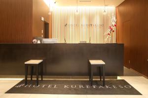 广岛Hotel Kuretakeso Hiroshima Otemachi的大厅,柜台前有两张凳子