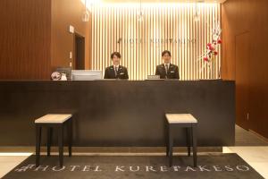 广岛Hotel Kuretakeso Hiroshima Otemachi的两名身着图西多斯服的男子坐在前台