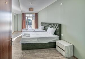 库塔伊西Four Seasons Riverside的一间卧室配有两张带白色床单的床