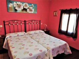 La MataCasa Rural La Dehesa的一间卧室设有红色的墙壁和一张带毯子的床