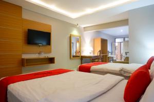 肯达利RedDoorz Plus at Hotel Srikandi Kendari的酒店客房设有两张床和一台平面电视。