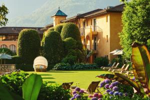 阿斯科纳阿斯科纳贾尔迪诺酒店的一个带椅子和树木的草坪的度假胜地