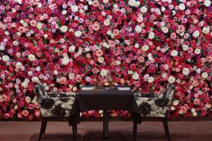 阿斯科纳阿斯科纳贾尔迪诺酒店的玫瑰墙前的一张桌子和两把椅子