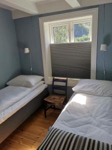 翁达尔斯内斯Østigård 1810的一间卧室设有两张床、一把椅子和一个窗户。