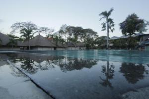 沙努尔阿里特海滩度假别墅酒店的一个棕榈树和建筑的空游泳池