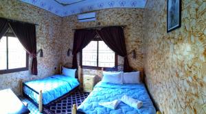 廷吉尔AUBERGE ROYAL PALMAS的一间卧室设有两张床和两个窗户。