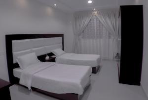 Hotat bani tamimروز للشقق الفندقية的酒店客房设有两张床和窗户。