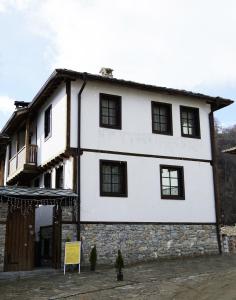 DelchevoGalabova Guest House的石砌建筑上带黑窗的白色房屋
