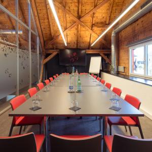 VionnazLe Manoir Vionnaz的大型会议室,配有长桌子和红色椅子