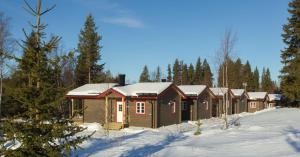 韦姆达伦Vålkojan Naturby - Timber cottages的森林中积雪中的一排小屋