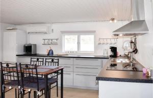 JÃ¤mjÃ¶2 Bedroom Gorgeous Home In Jmj的厨房配有白色橱柜和桌椅