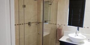 鲁德普特Gold Crest Guesthouse的一间带玻璃淋浴和水槽的浴室