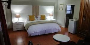 鲁德普特Gold Crest Guesthouse的一间卧室配有一张带两张桌子和两盏灯的床。