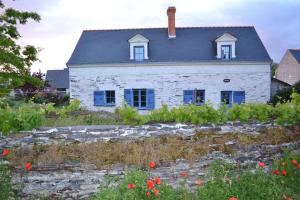 La Daguenière德格鲁瓦度假屋的白色的古老房子,拥有蓝色的窗户和鲜花