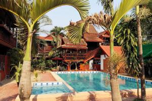 沙拉丕金色柚木度假村的一个带游泳池和棕榈树的度假村