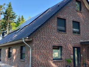 瓦尔斯罗德Ferienwohnung Hünzingen的屋顶上设有太阳能电池板的红砖房子