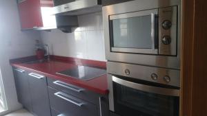 卢戈Precioso apartamento的厨房配有微波炉和红色台面