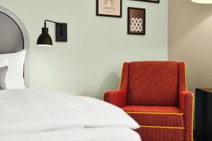 波茨坦MAXX Hotel Sanssouci Potsdam的一间卧室配有红色椅子和一张床
