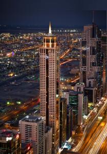 迪拜The Tower Plaza Hotel Dubai的夜晚在城市的高楼