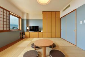 叶山町Hayama Umino Hotel的一间配备有桌子和两把椅子及一台电视的房间