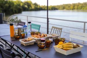 南特La Rivière House - Péniche Carpe Diem的水边的桌子上放着面包和其他食物