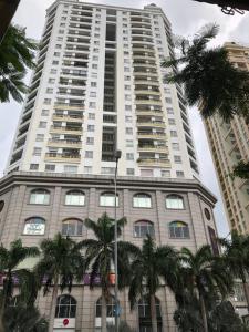 胡志明市Khách sạn Trường Sơn的一座高大的建筑,前面有棕榈树