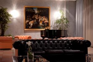 维罗纳Hotel Palace Verona的客厅里一张黑色皮沙发,配有绘画作品