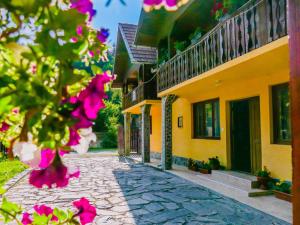 克尔茨什瓦拉乡Casa Ursu的一条鹅卵石街道,旁边是一座黄色的建筑,花朵粉红色