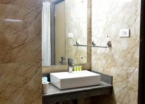 瓦拉纳西城市客栈酒店的浴室设有白色水槽和镜子