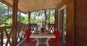 莫列马阿VVF Landes Moliets的小屋门廊上的一张桌子和红色的椅子