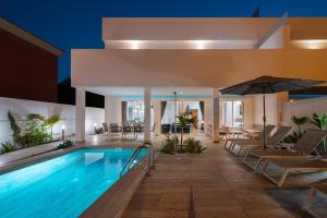 马斯帕洛马斯Villa Deluxe Suites Maspalomas的一个带椅子和遮阳伞的酒店游泳池