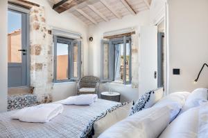干尼亚Aoria Estate Old Port的卧室拥有白色的墙壁和窗户,配有带枕头的床铺。