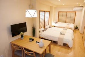 东京Ueno Residence Hotel Matsumoto的一间卧室配有两张床、一张桌子和一台电视。