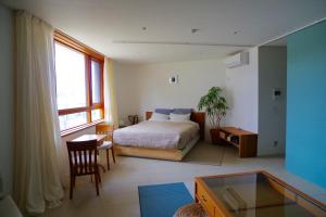 藤泽片濑珊瑚公寓的一间卧室配有一张床、一张书桌和一个窗户。