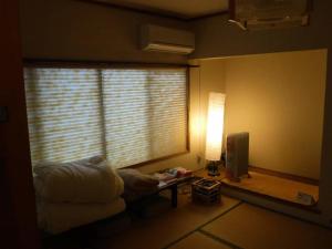 广岛广岛日式旅馆的客厅设有窗户、桌子和台灯