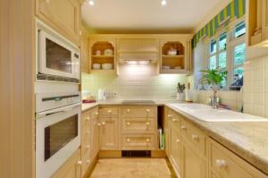 吉尔福德White Lodge House的厨房配有白色家电和木制橱柜