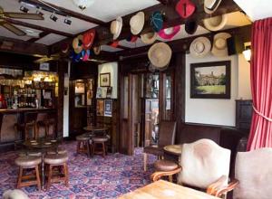 威姆斯洛The Kings Arms的一间房间,墙上挂着一顶帽子,有一个酒吧