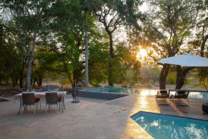 侯斯普瑞特Southern Sands Eco Lodge的一个带桌子和遮阳伞的庭院,毗邻一个游泳池